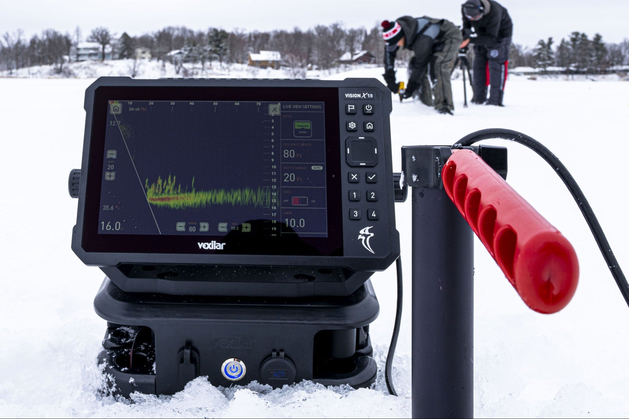 Fishing sonar device on a snowy ground with people in the background